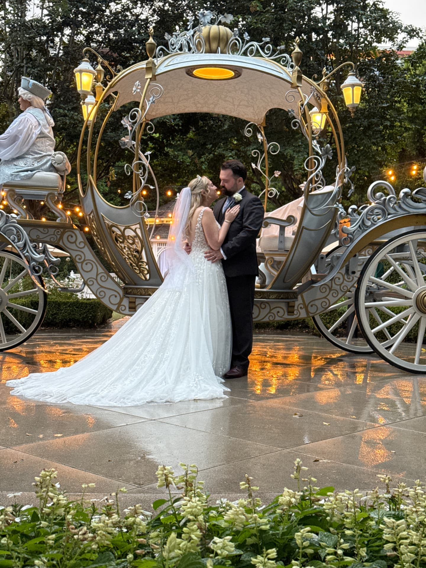 Newlyweds embracing beside Cinderella's carriage at Disneyland